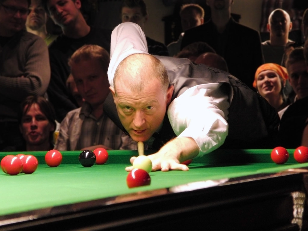 A snooker player lines up a shot while spectators watch